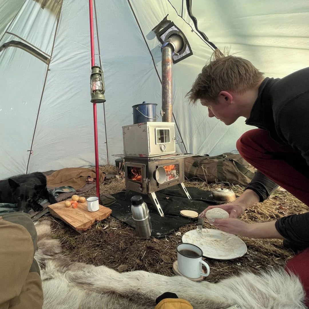 Winnerwell Nomad View brennend in einem Zelt, ein Mann legt Essen auf einen Teller