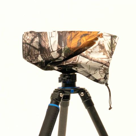 Housse de pluie Buteo 1 en camouflage branches clair sur un objectif monté sur trépied, avec arrêt de cordon