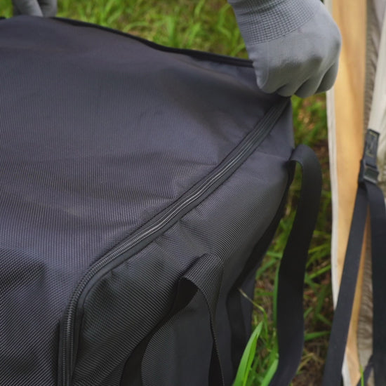persoon met hittebestendige handschoen bij een brandende tentkachel met glazen raam, schoorsteenpijp en waterketel bovenop in een tentomgeving