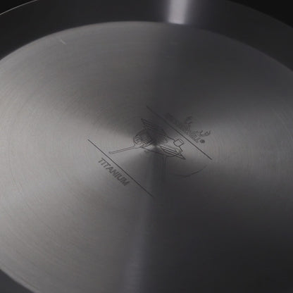 close-up van de binnenkant van een titanium koekenpan met gegraveerd logo en tekst in het midden