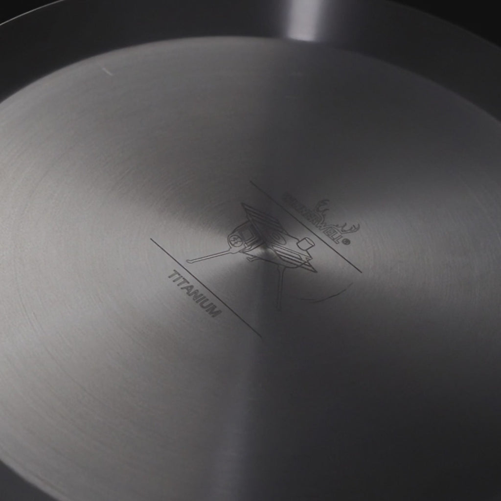 close-up van de binnenkant van een titanium koekenpan met gegraveerd logo en tekst in het midden