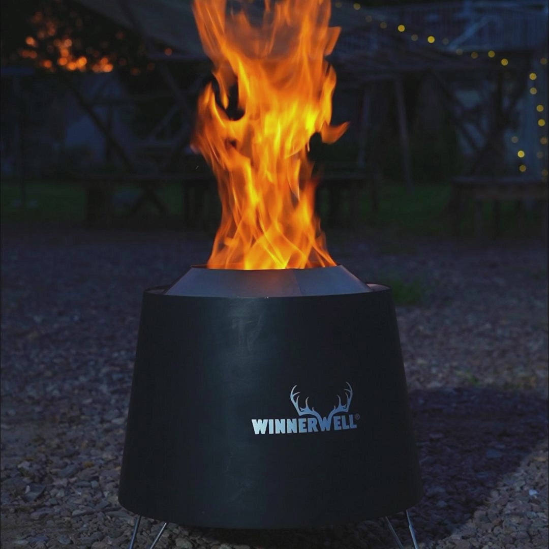brandende smokeless fire pit met hoge vlammen uit de bovenkant, geplaatst op een grindondergrond met zichtbaar Winnerwell-logo aan de voorkant
