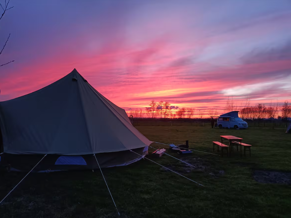 Sibley ProTech 500 tent van CanvasCamp op de proefslaaplocatie bij Camping Zwolsedijk tijdens een roze zonsondergang met een busje en picknicktafel in het veld.