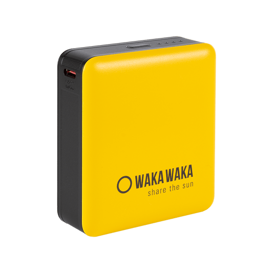 Een compacte geel-zwarte powerbank met afgeronde hoeken, met bovenop kleine indicatorlampjes en aan de zijkant een oplaadpoort; op de voorkant staat het WakaWaka-logo met de tekst “share the sun”.
